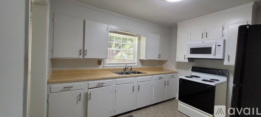 A kitchen with white cabinets and a black refrigerator.