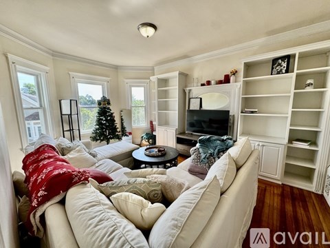 A living room with a Christmas tree and a couch with a red blanket on it.
