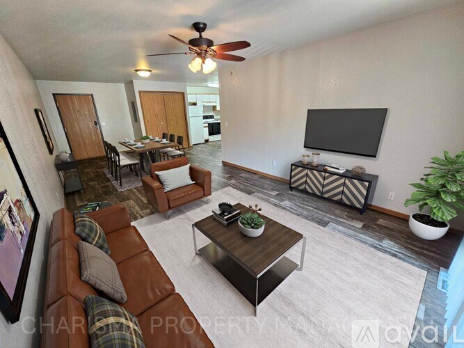 A living room with a brown leather couch, a coffee table, and a flat screen TV.