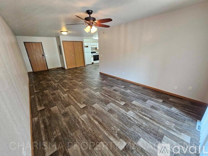 A room with a ceiling fan and wooden flooring.