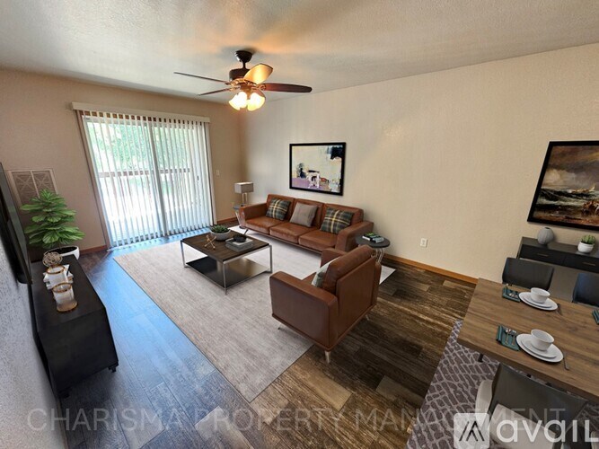A living room with a brown couch, a coffee table, and a ceiling fan.