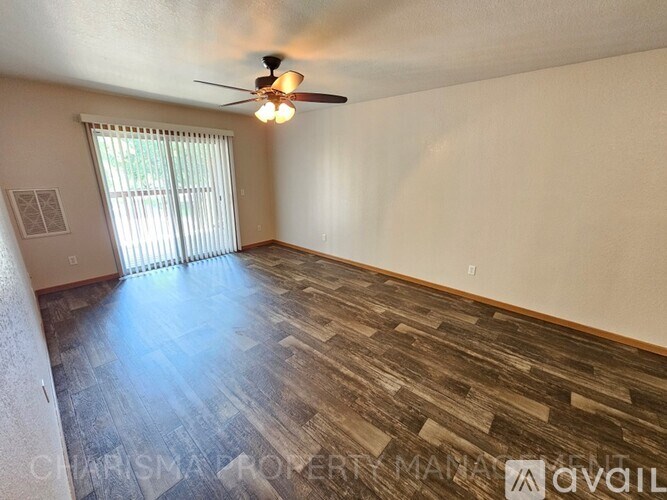 A room with a ceiling fan and wooden flooring.
