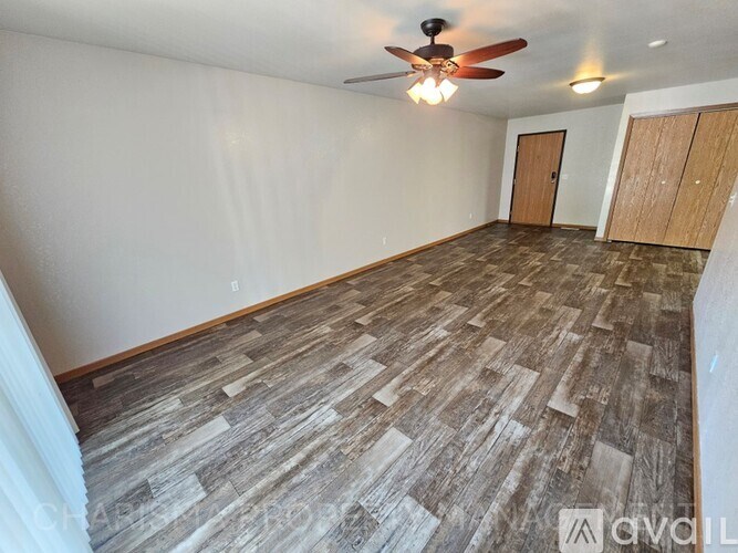 A room with a ceiling fan and wood flooring.