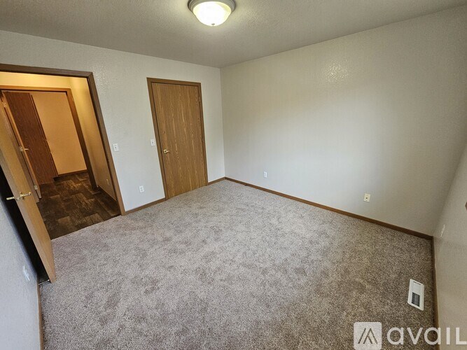 A carpeted room with a door and a light on the ceiling.