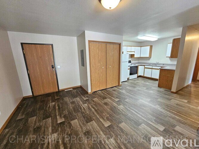 A spacious room with wooden flooring and two doors leading to another room.