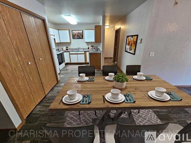 A dining area with a table set for four with a view of the kitchen.
