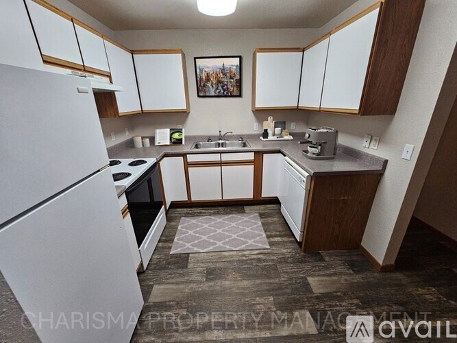 A kitchen with white appliances and wooden cabinets.