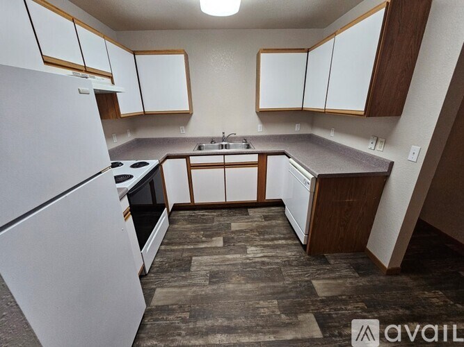 A kitchen with a white refrigerator, wooden cabinets, and a black stove top oven.
