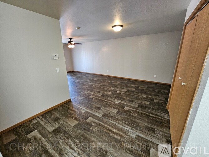 A room with a ceiling fan and wood flooring.