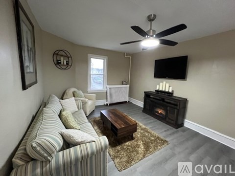 A living room with a striped couch, a coffee table, and a television mounted on the wall.
