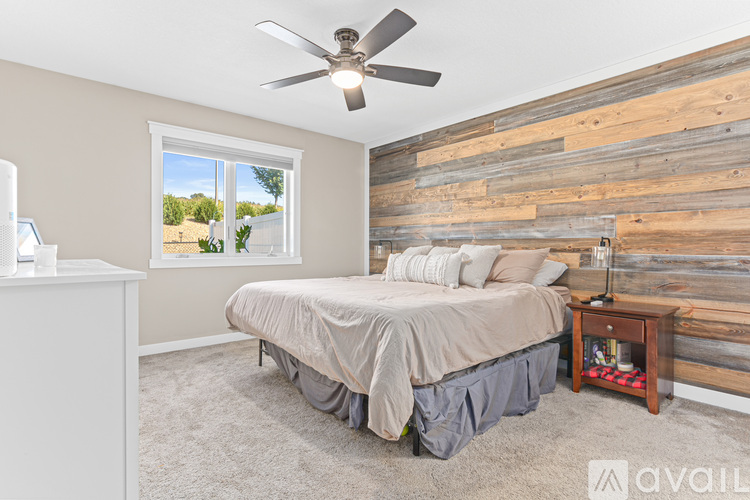 A bedroom with a bed, a dresser, and a window with a view of the outdoors.