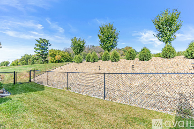 A fenced area with a grassy field and trees in the background.