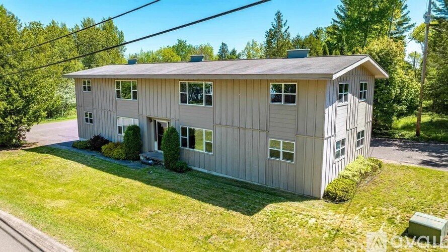 A two-story house with a grey exterior and a green lawn in front.
