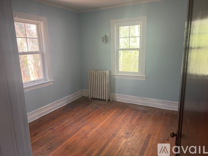A room with a wooden floor and a window with a white frame.