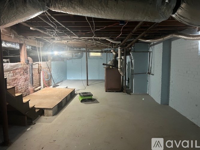 A room with a concrete floor and a brick wall on the left side.