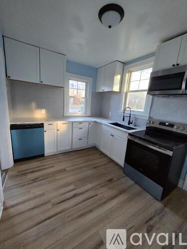 A kitchen with white cabinets and a wooden floor.