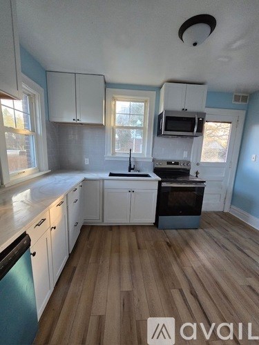 A kitchen with white cabinets and a wooden floor.