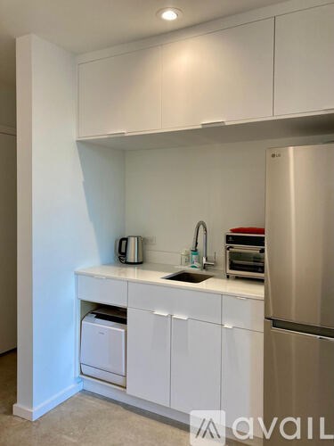 A kitchen with white cabinets and a stainless steel refrigerator.