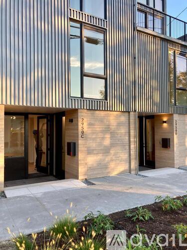 A modern house entrance with a wooden wall and a black door.