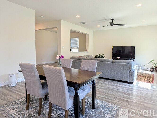 A modern dining room with a wooden table and grey chairs.