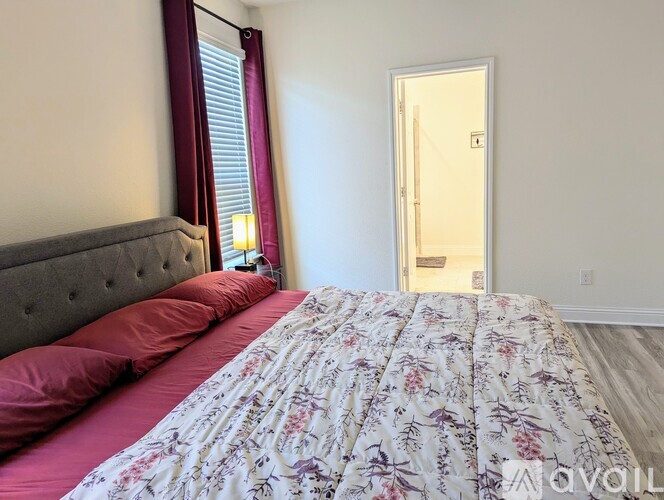 A bedroom with a bed, pillows, and a window with curtains.