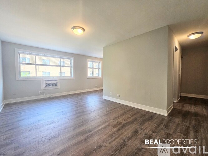 A spacious room with a large window and a wooden floor.