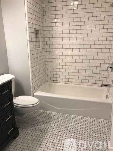 A white tiled bathroom with a toilet, a bathtub and a cabinet.