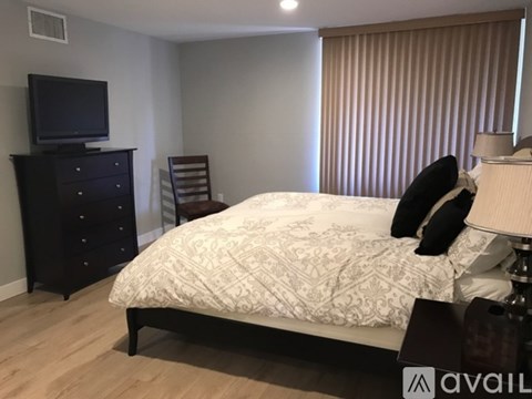 A bedroom with a bed, a dresser, and a television.