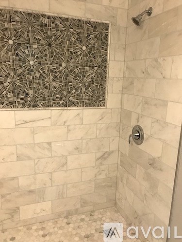 A shower with a tile border and a tile floor.