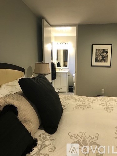 A bedroom with a bed, lamp, and framed picture on the wall.