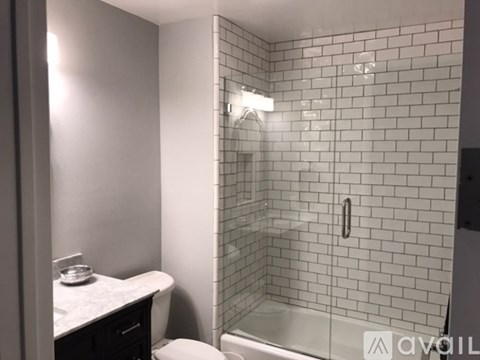 A white toilet sits next to a walk-in shower with a glass door.