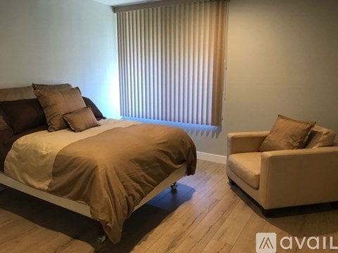 A bedroom with a bed and a chair.