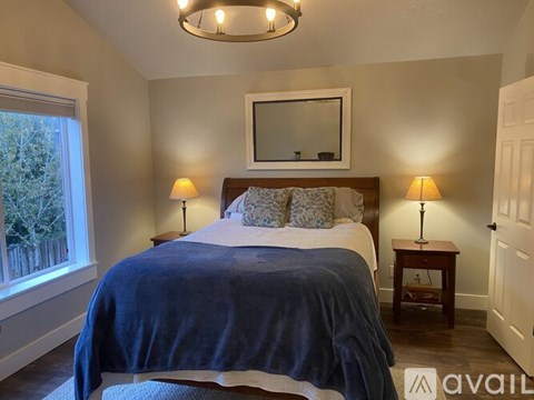 A bedroom with a bed, two lamps, and a mirror on the wall.