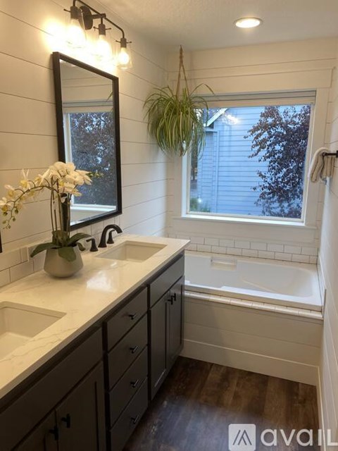 A bathroom with a large mirror, a white sink, and a bathtub.