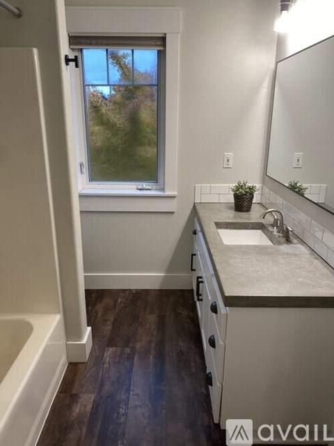 A bathroom with a tub, sink, and mirror.
