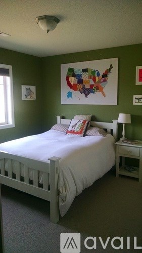 A bedroom with a bed, nightstand, and a map of the United States on the wall.