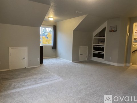 A spacious room with a basketball hoop and a window with a view of trees.