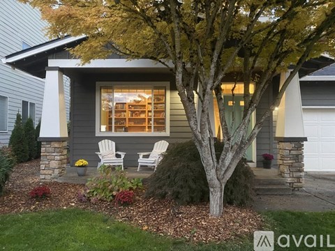 A house with a tree in front and two chairs on the porch.