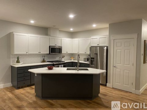 A modern kitchen with a central island and wooden flooring.