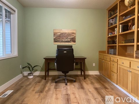 A room with a desk, chair, and a painting on the wall.