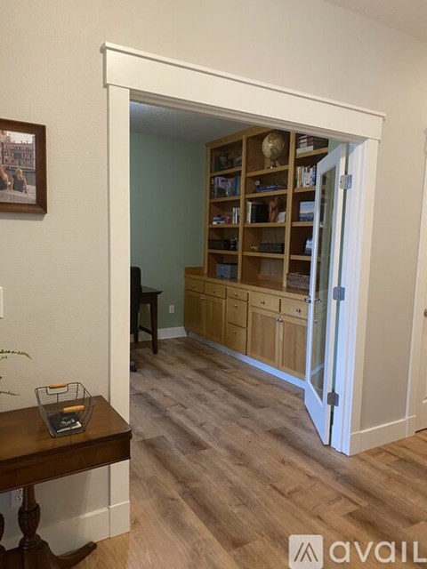 A room with a wooden floor and a bookshelf with books and decorations.