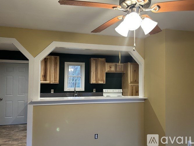 A kitchen with a fan and a window with curtains.