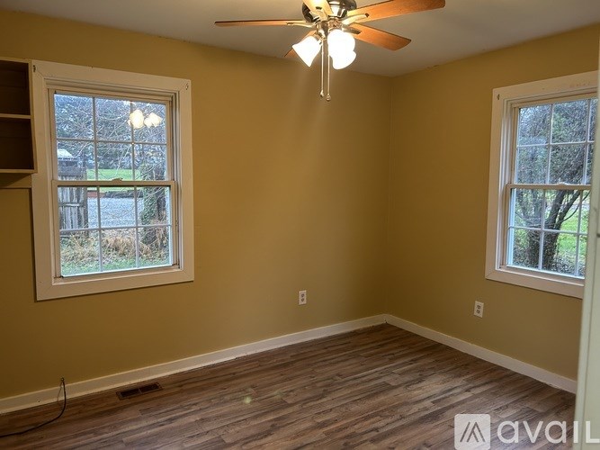 A room with a ceiling fan and two windows.