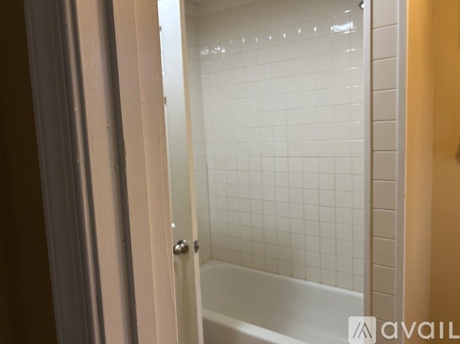 A white tiled shower stall with a door.