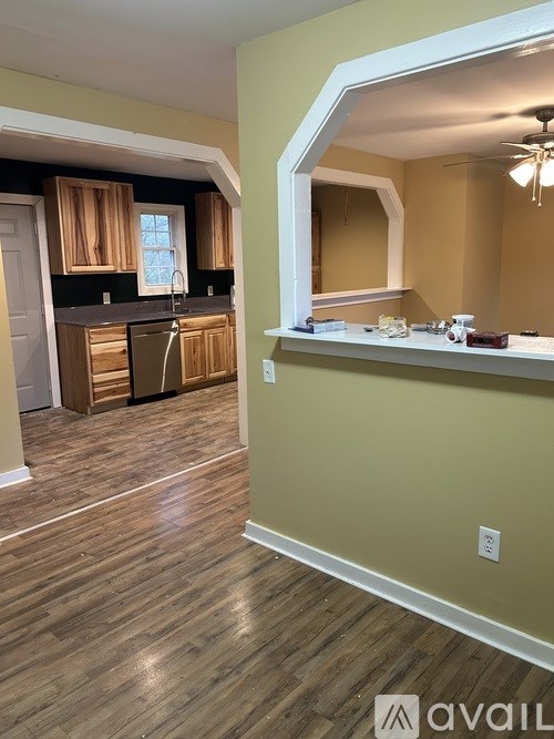 A room with wooden flooring and a counter with a mirror above it.