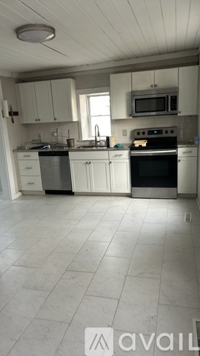 A kitchen with white cabinets and appliances.