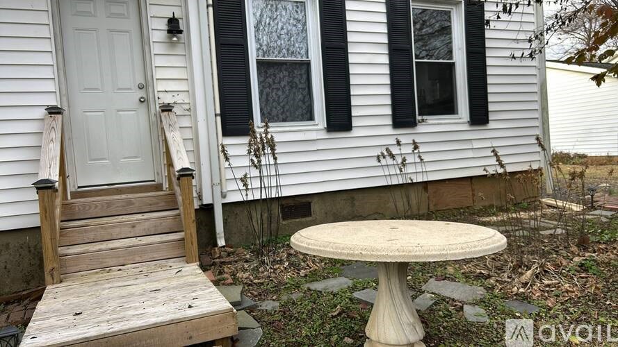 A white house with a wooden staircase and a round table.