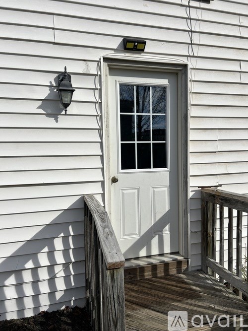 A white door with a window and a lantern on the wall.