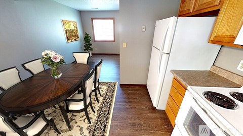A kitchen with a table and chairs in the foreground and a refrigerator in the background.