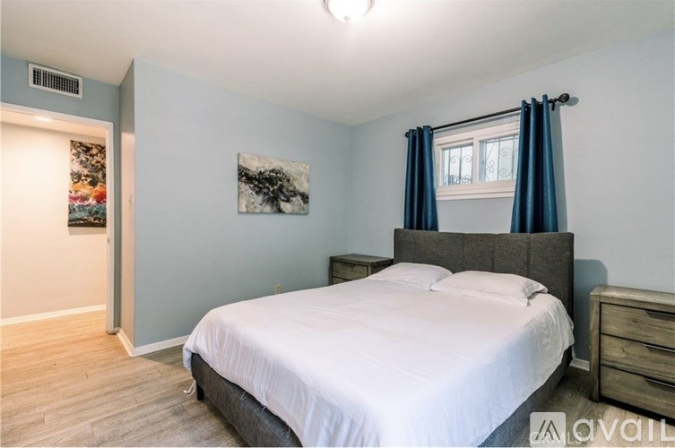 A bedroom with a bed, nightstand, and a painting on the wall.